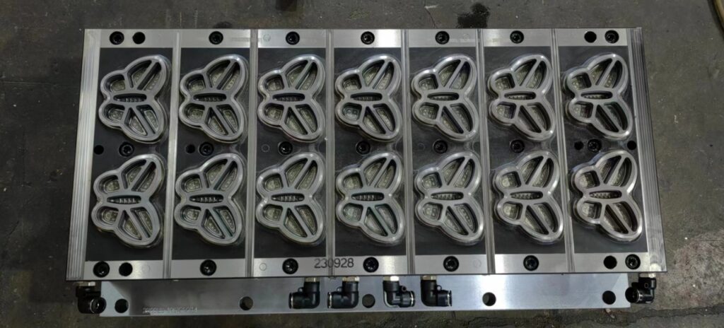 Butterfly-shaped metal mold on industrial surface.