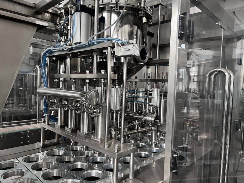 Close-up of the piston filling nozzle dispensing mayonnaise into cups