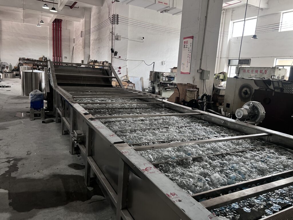An auto pasteurizer machine showing jelly cups moving through a hot water bath