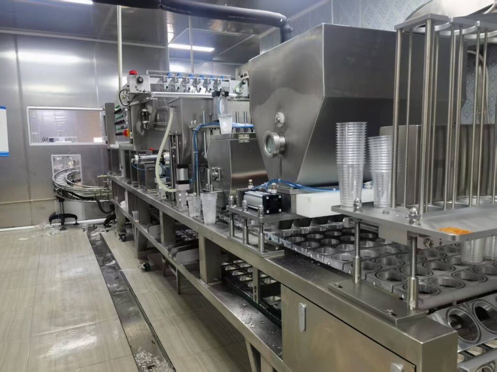 A modern ice cup filling and sealing machine in a clean factory setting.