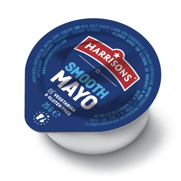A cup of freshly packed mayonnaise next to a modern filling and sealing machine