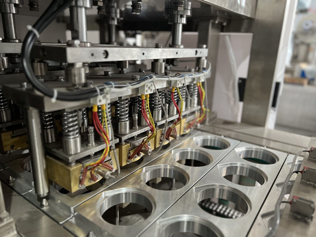 A clean, flat metal sealing head component from a packaging machine