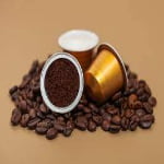 Coffee capsules and ground coffee on coffee beans.