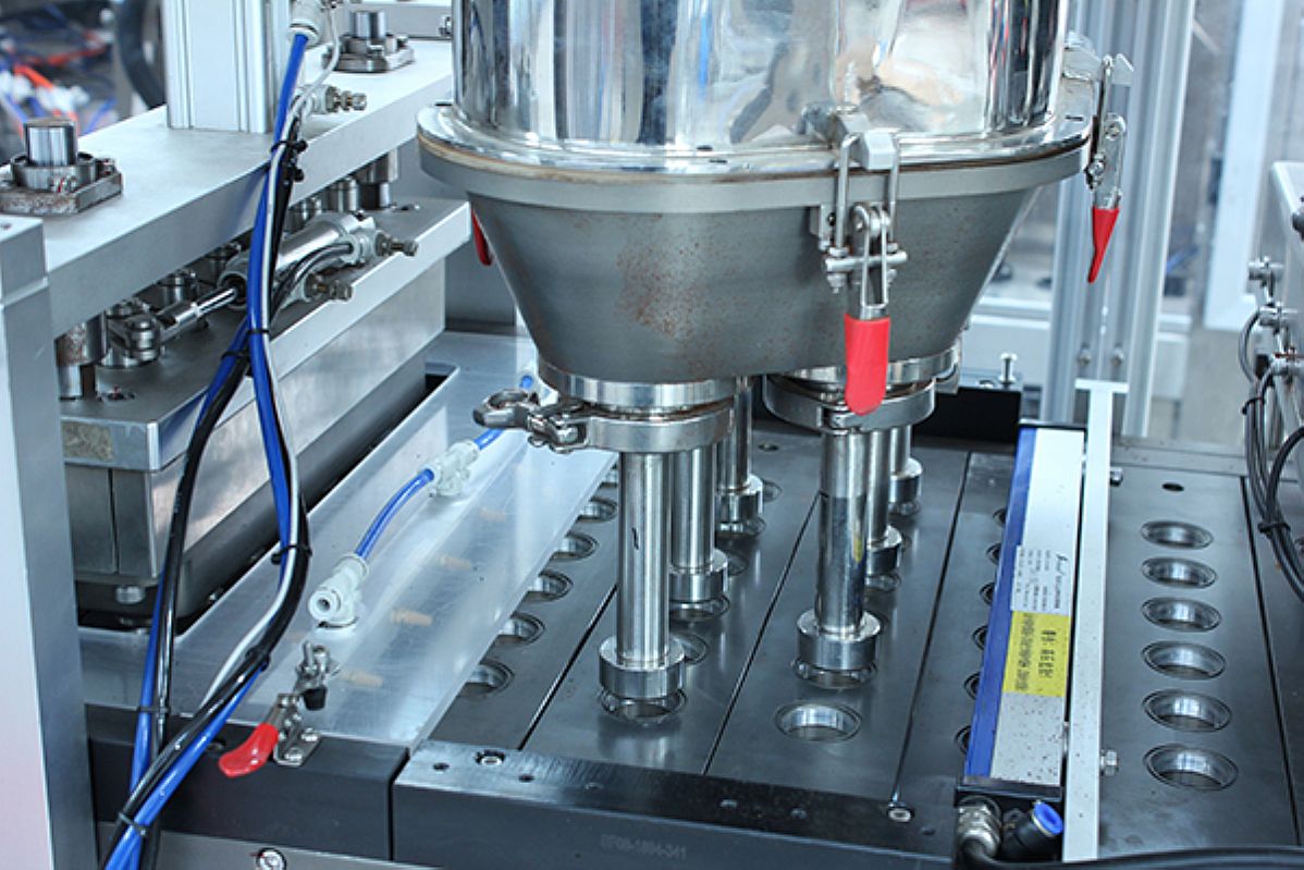 Close-up of the auger filler dispensing coffee powder into a K-cup