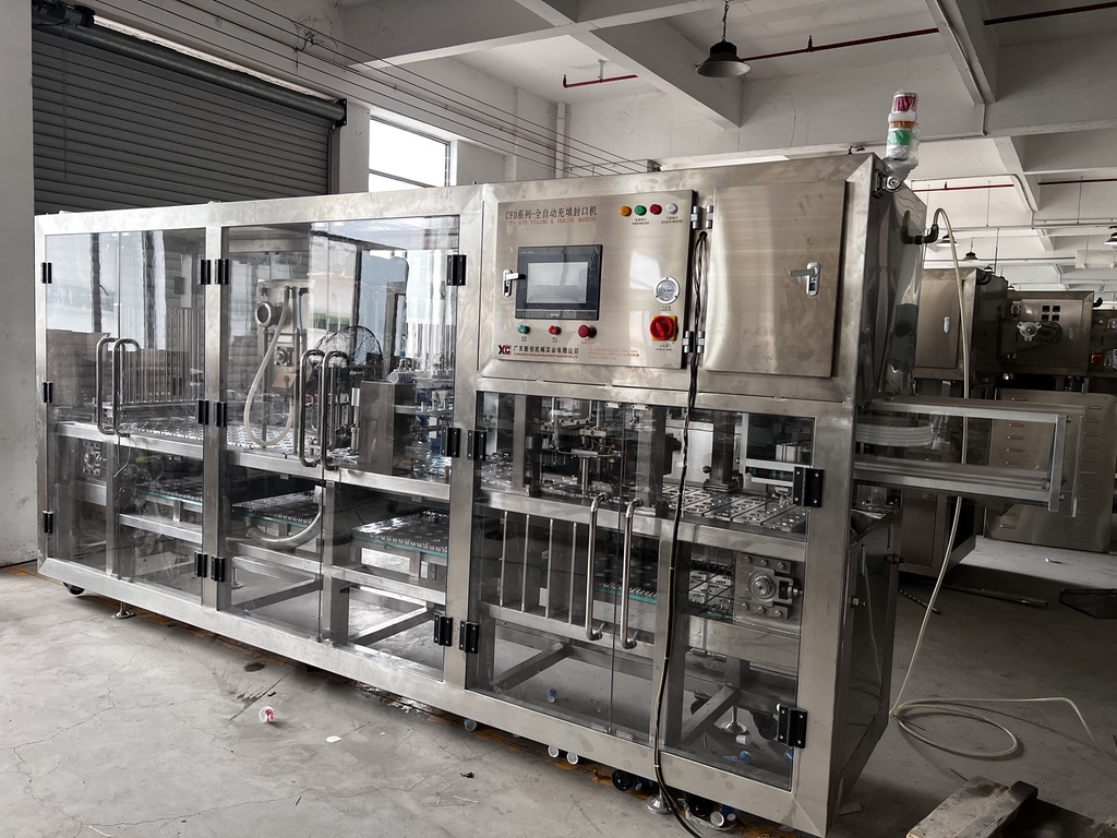 An automated K-cup filling and sealing machine in a factory setting