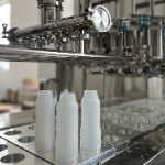 Three empty white bottles on a stainless steel table.