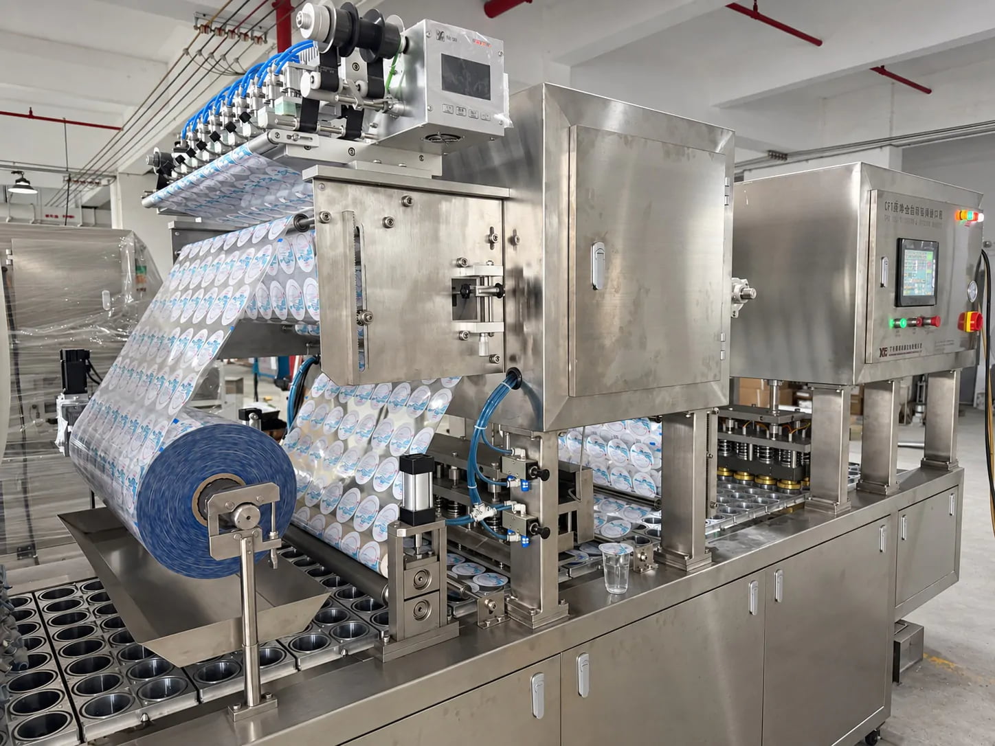 Real factory view of an automatic cup filling and sealing machine with printed roll film