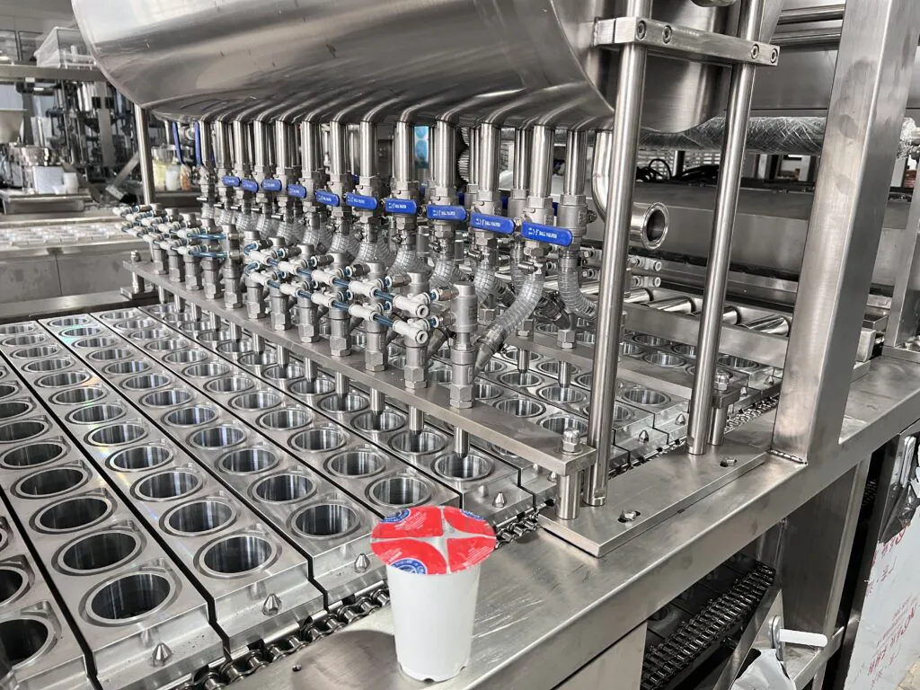 Industrial yogurt filling and packaging machine in factory.