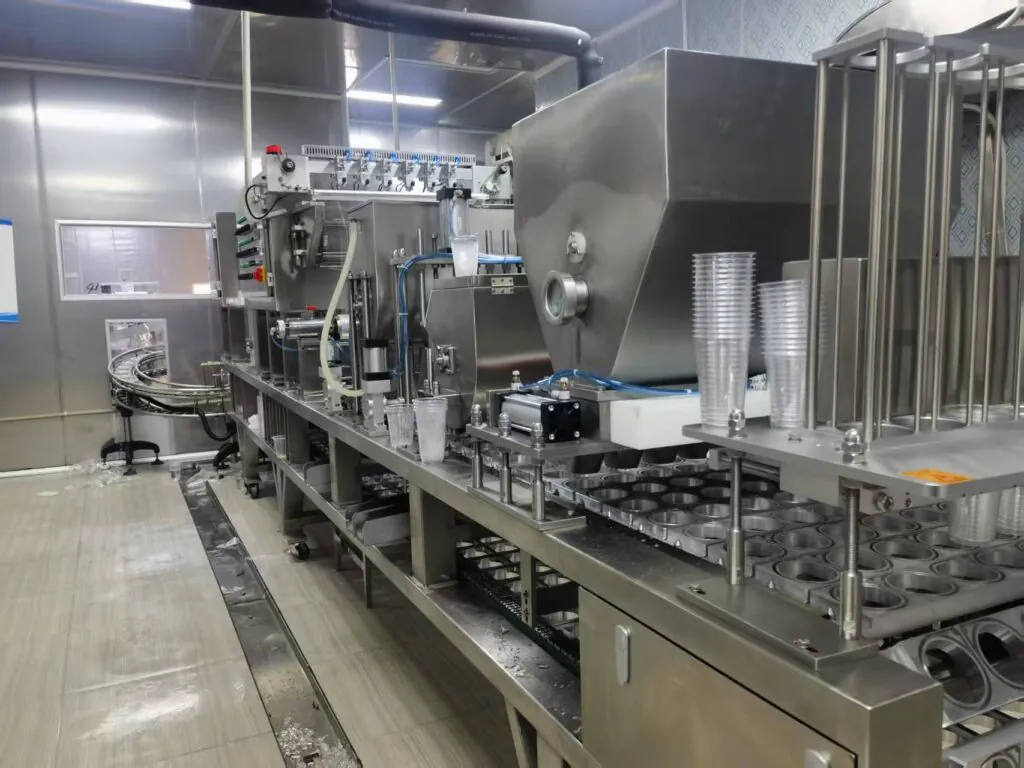 A modern ice cup filling and sealing machine in a clean factory setting.